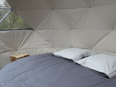 Dôme géodésique à Grand-Est, intérieur cosy avec lit rond et grandes fenêtres.