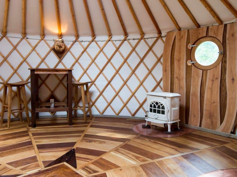 Intérieur dune yourte, avec un poêle élégant et un mobilier en bois chaleureux.