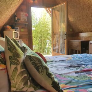 Cabane en bois avec lit coloré et vue sur la nature verdoyante.