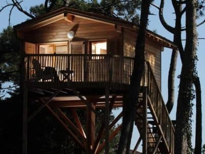 Cabane perchée en bois dans les arbres, entourée de pins en Aquitaine.
