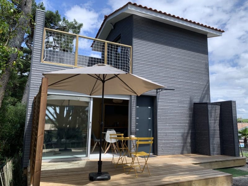 Hébergement insolite en Aquitaine : maison moderne avec terrasse et parasol.