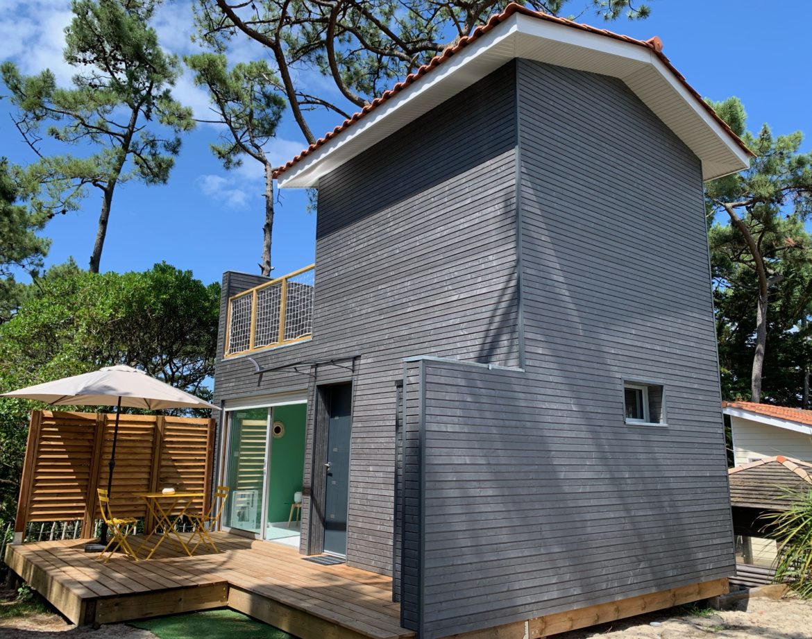 Cabane moderne en bois avec terrasse, entourée de verdure en Aquitaine.