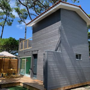 Cabane moderne en bois avec terrasse, entourée de verdure en Aquitaine.