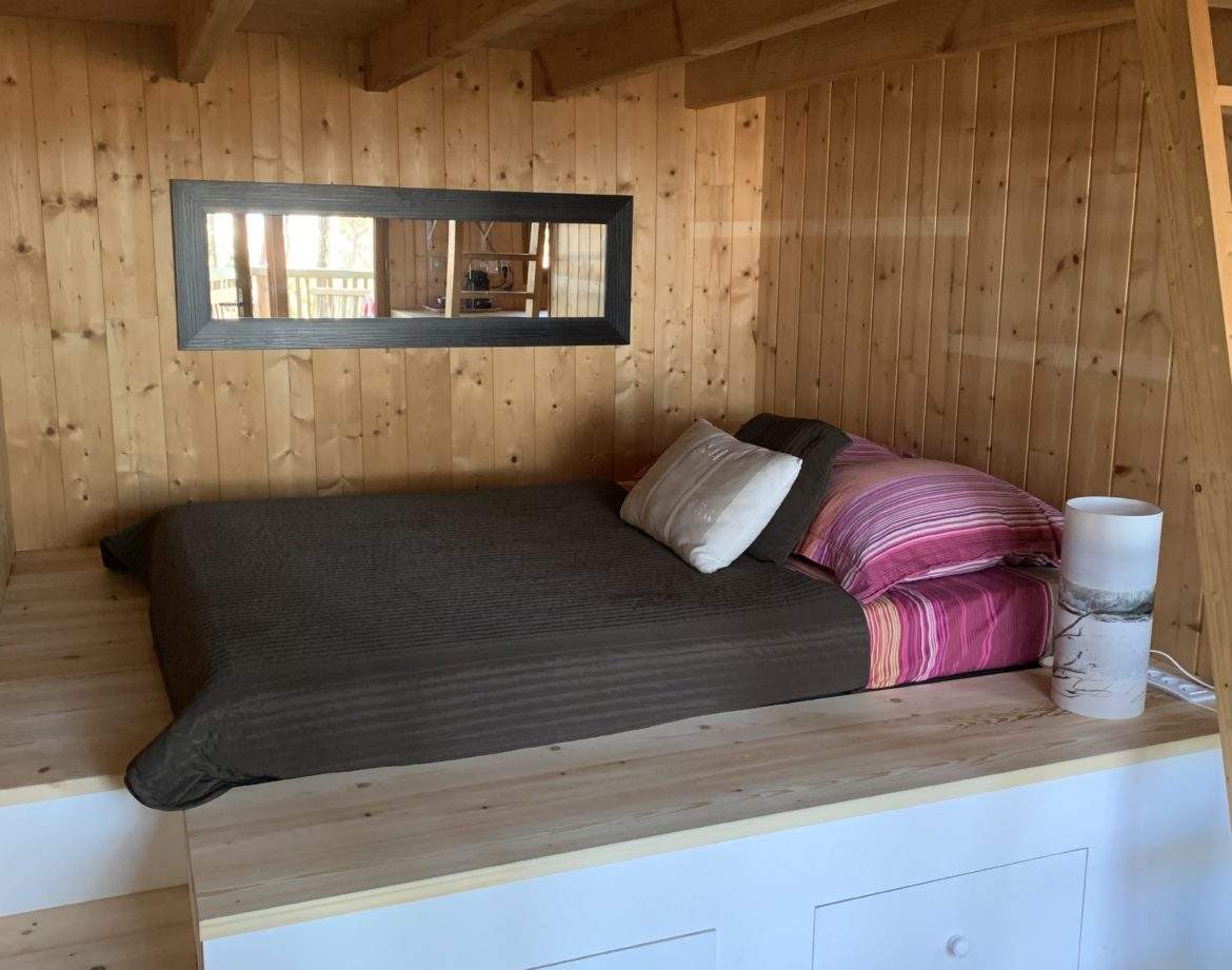 Chalet en bois avec lit douillet et décoration chaleureuse en Aquitaine.