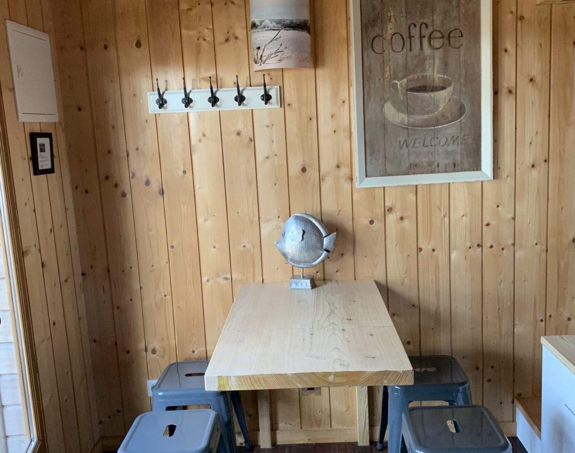 Cabane en bois en Aquitaine, avec une table en bois et des chaises métalliques.