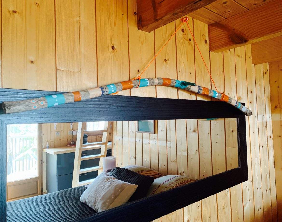 Cabane en bois en Aquitaine, miroir décoré avec une branche colorée.