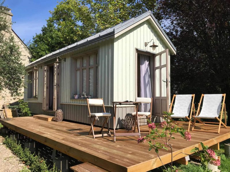 Charmante cabane en bois avec terrasse en bois et chaises longues.