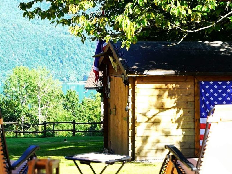 Chalet en bois avec vue sur le lac, drapeau américain accroché à lextérieur.