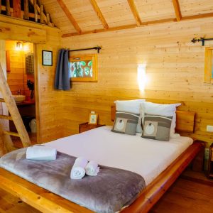 Cabane en bois chaleureuse avec lit douillet et décoration naturelle.