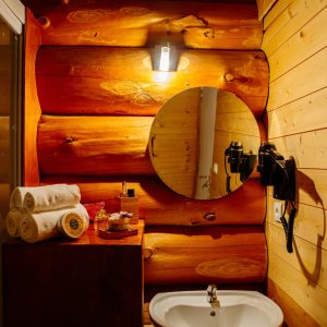 Salle de bain en bois dans un hébergement insolite en Aquitaine, avec miroir rond.