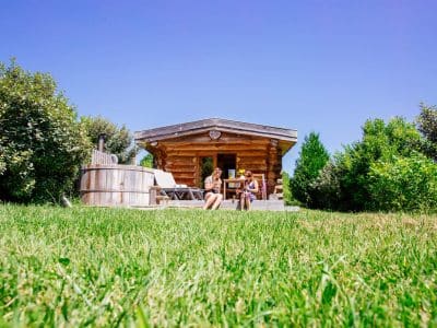 Cabane en bois avec jacuzzi, entourée de verdure en Aquitaine. Détente au soleil.