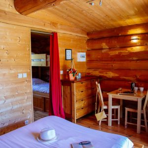 Chalet en bois chaleureux avec lit confortable et coin repas lumineux.