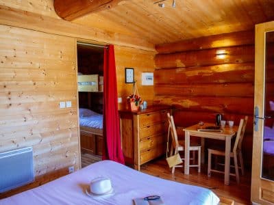 Chalet en bois chaleureux avec lit confortable et coin repas lumineux.