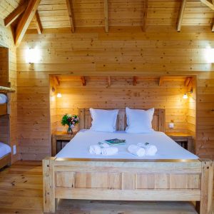 Chalet en bois chaleureux avec lit double et lits superposés, ambiance cosy.