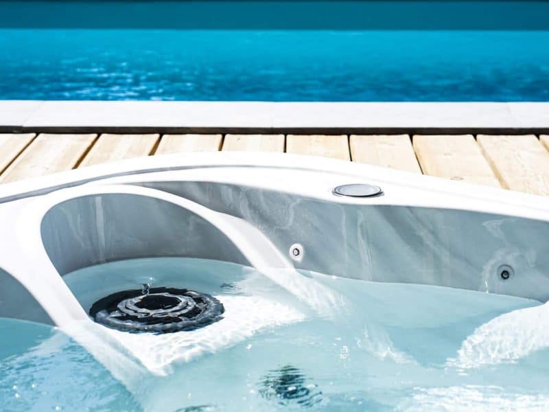 Jacuzzi relaxant au bord dune piscine turquoise, idéal pour se détendre.