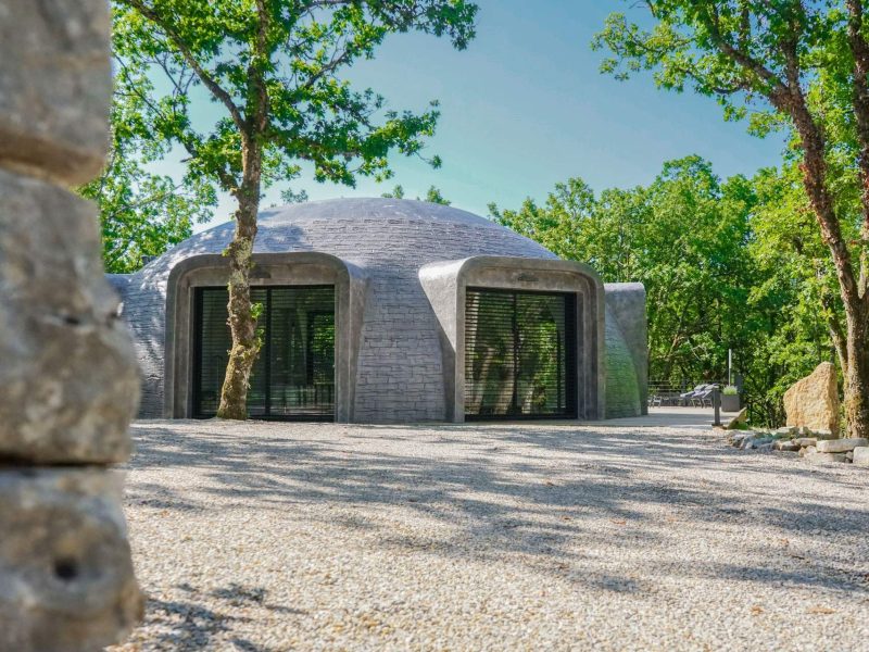 Hébergement touristique moderne en forme de dôme, entouré darbres verdoyants.