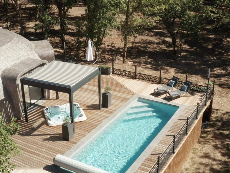 Dôme moderne avec piscine et jacuzzi, entouré de verdure apaisante.
