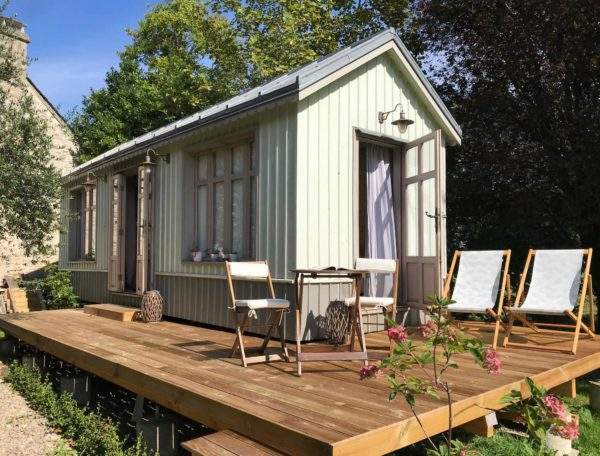 Charmante cabane en bois avec terrasse en bois et chaises longues.