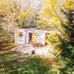 Cabane en bois dans les arbres, entourée de feuillage doré en Aquitaine.