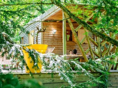 Cabane perchée en Aquitaine, entourée de verdure, avec terrasse en bois accueillante.