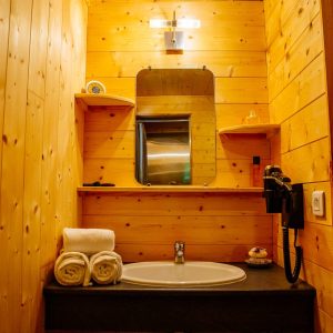 Salle de bain en bois dans un hébergement insolite en Aquitaine, avec lavabo et miroir.