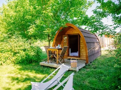 Cabane en bois en Aquitaine, entourée de verdure, avec terrasse et chaises longues.