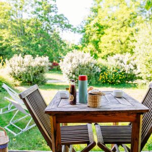 Hébergement insolite en Aquitaine : table en bois avec vue sur un jardin verdoyant.