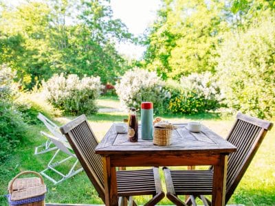 Hébergement insolite en Aquitaine : table en bois avec vue sur un jardin verdoyant.