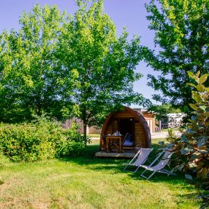 Cabane en bois au milieu de la verdure, avec chaises longues à lextérieur.