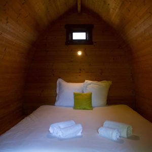Cabane en bois cosy avec lit douillet et lumière douce, idéale pour un séjour unique.