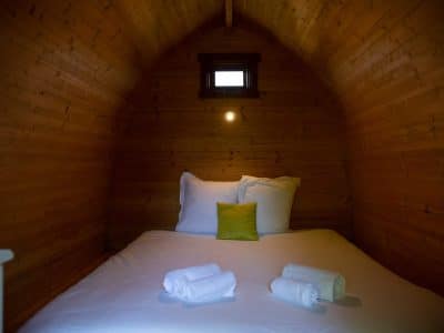 Cabane en bois cosy avec lit douillet et lumière douce, idéale pour un séjour unique.