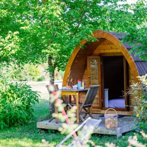 Cabane en bois en Aquitaine, entourée de verdure, avec terrasse et mobilier extérieur.
