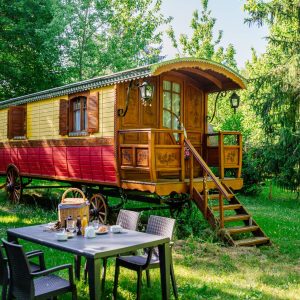 Charmante roulotte colorée en bois, entourée de verdure, idéale pour un séjour insolite.