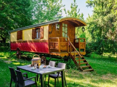 Charmante roulotte colorée en bois, entourée de verdure, idéale pour un séjour insolite.