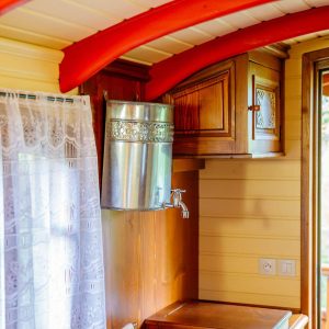 Intérieur dune roulotte en Aquitaine, avec des poutres rouges et un évier en bois.
