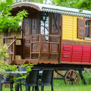Charmante roulotte colorée avec balustrade en bois, entourée de verdure en Aquitaine.