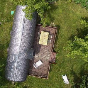 Hébergement insolite en Aquitaine : un roulotte sur une terrasse en bois entourée de verdure.