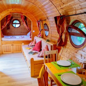 Hébergement insolite en Aquitaine : roulotte en bois avec fenêtres rondes et décor chaleureux.