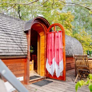 Hébergement insolite en Aquitaine : cabane en bois avec porte arrondie et terrasse accueillante.