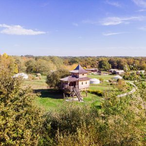 Cabane perchée en bois avec un toit pointu, entourée de verdure en Aquitaine.