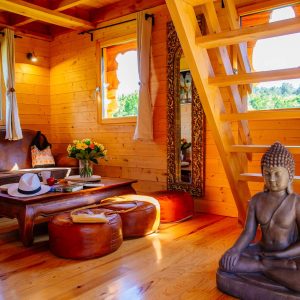 Cabane en bois avec un intérieur chaleureux et une statue de Bouddha décorative.