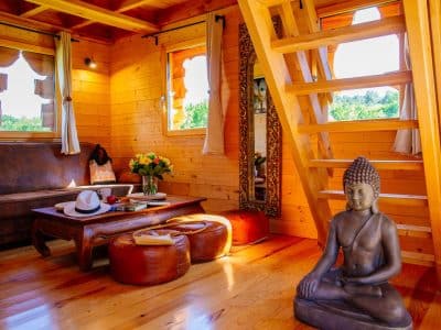 Cabane en bois avec un intérieur chaleureux et une statue de Bouddha décorative.