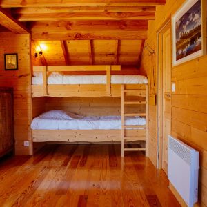 Chalet en bois avec lits superposés, ambiance chaleureuse et lumineuse.