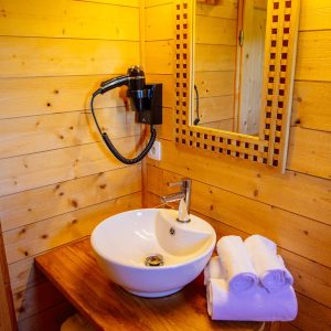 Salle de bain en bois dans un hébergement insolite en Aquitaine, avec lavabo moderne.