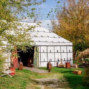 Tente marocaine spacieuse en Aquitaine, entourée de verdure et de mobilier coloré.