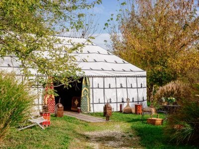 Tente marocaine spacieuse en Aquitaine, entourée de verdure et de mobilier coloré.