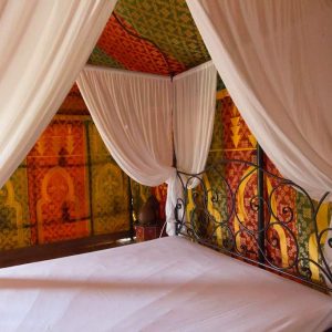 Tente berbère colorée avec lit en fer forgé, ambiance chaleureuse et accueillante.