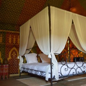 Tente luxueuse en Aquitaine, lit à baldaquin et décoration colorée.