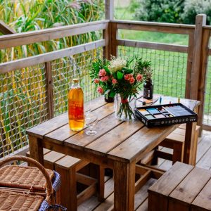 Hébergement insolite en Aquitaine : terrasse en bois avec fleurs et bouteille de vin.