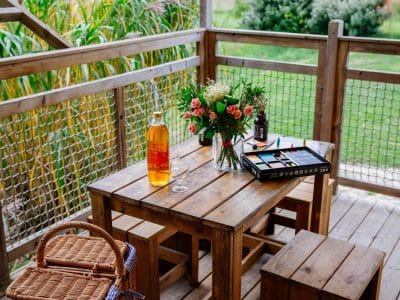 Hébergement insolite en Aquitaine : terrasse en bois avec fleurs et bouteille de vin.